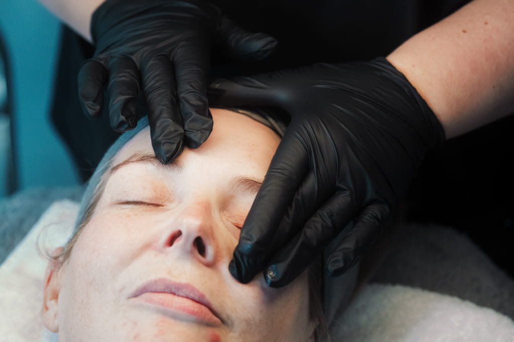 A Skin Therapist at Dr Lauren’s clinic preparing to give a facial to a patient.