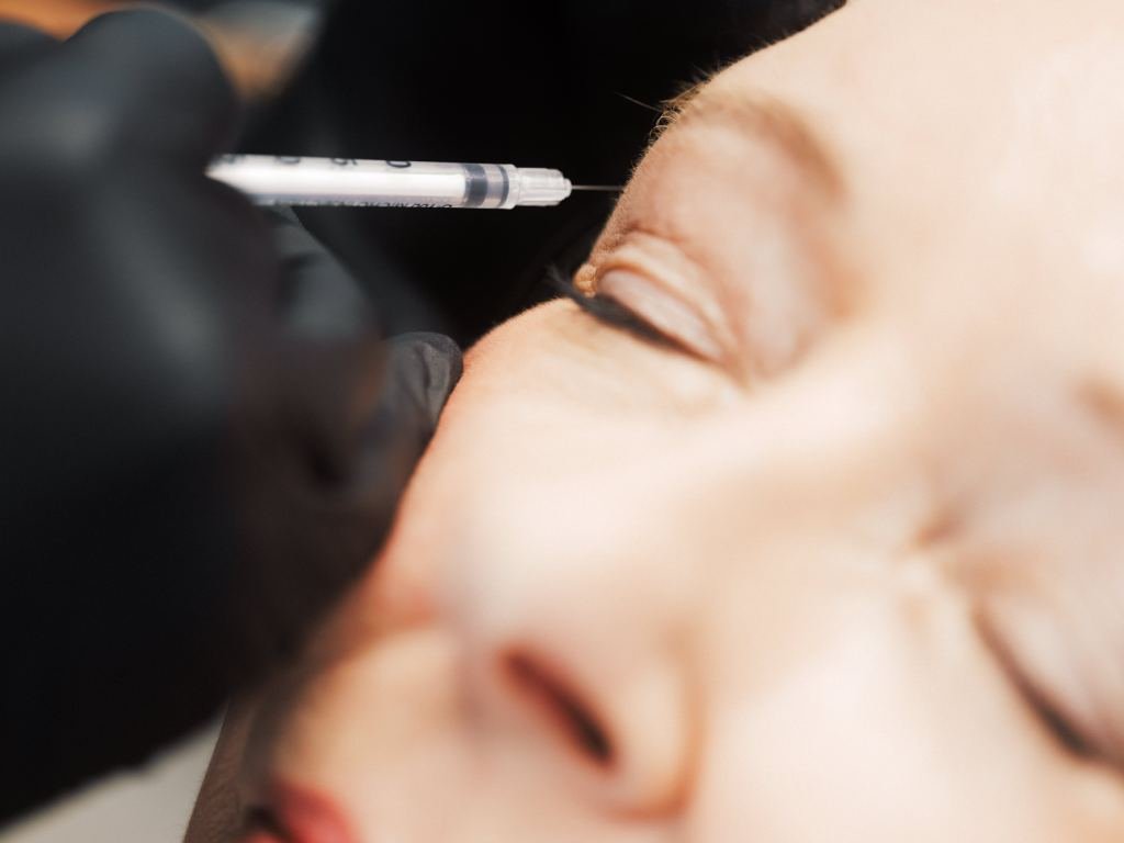 Dr. Lauren injecting a dermal filler in a patient's eyebrow area.