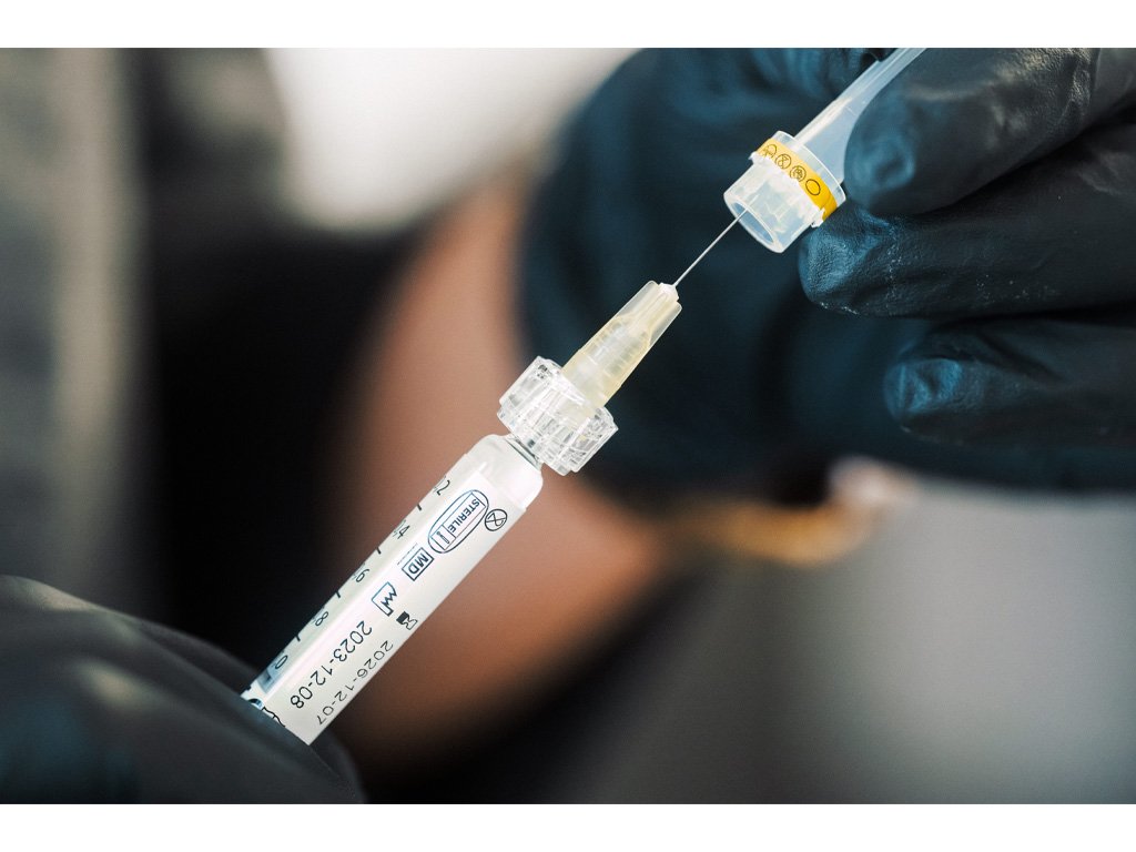 Dr Lauren placing a safety cap on a medical syringe to be used for lip fillers on a patient.