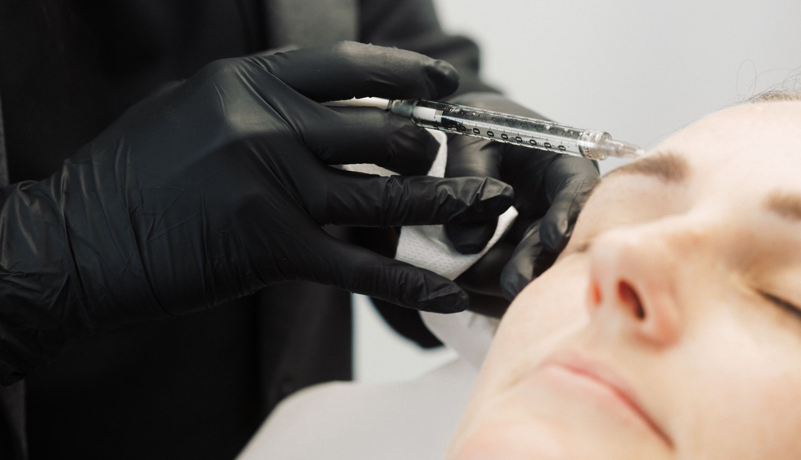 Dr Lauren injecting dermal filler in a patient's eyebrow area.