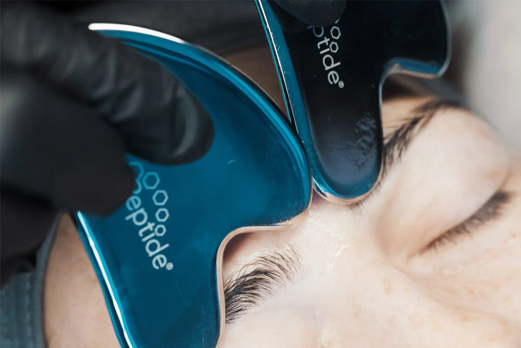 A Skin Therapist at Dr Lauren's clinic massaging a patient's face with HydroPeptide facial tools.